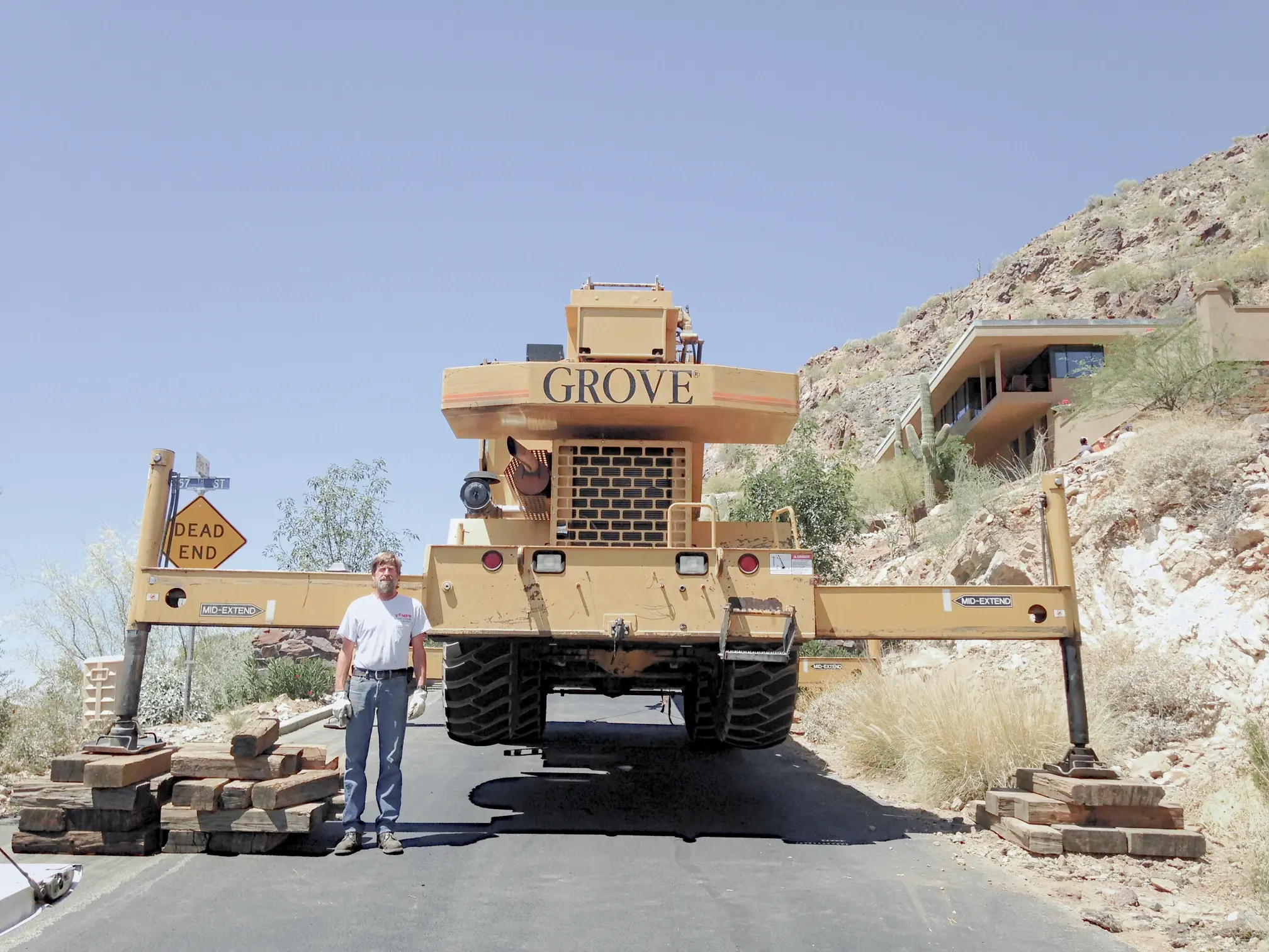 A worker stands behind a large 'rough terrain' crane set on blocks, highlighting its adaptability in challenging environments.