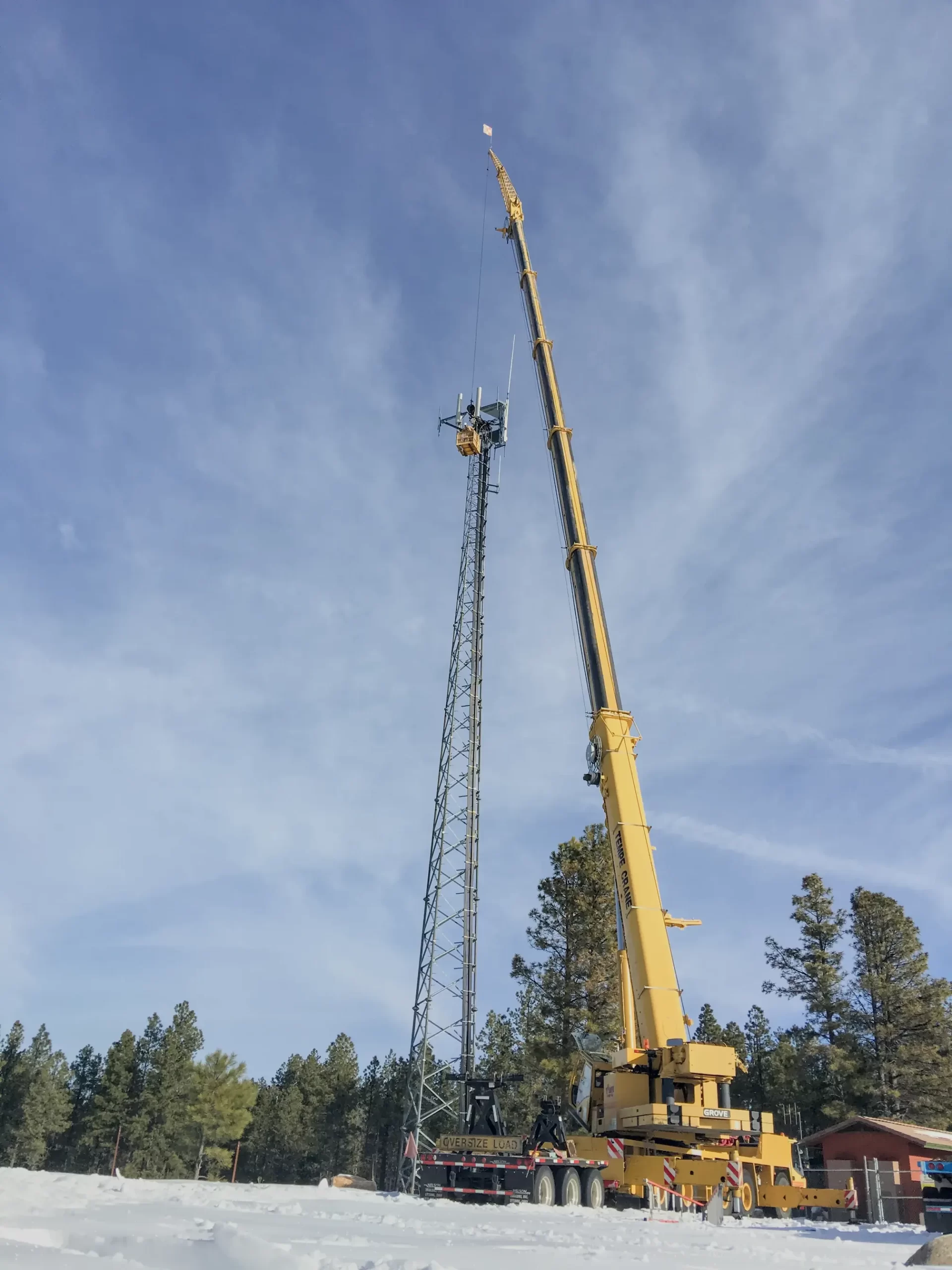 Specialized crane service elevating workers to service a cell tower, underpinning the importance of seamless connectivity.