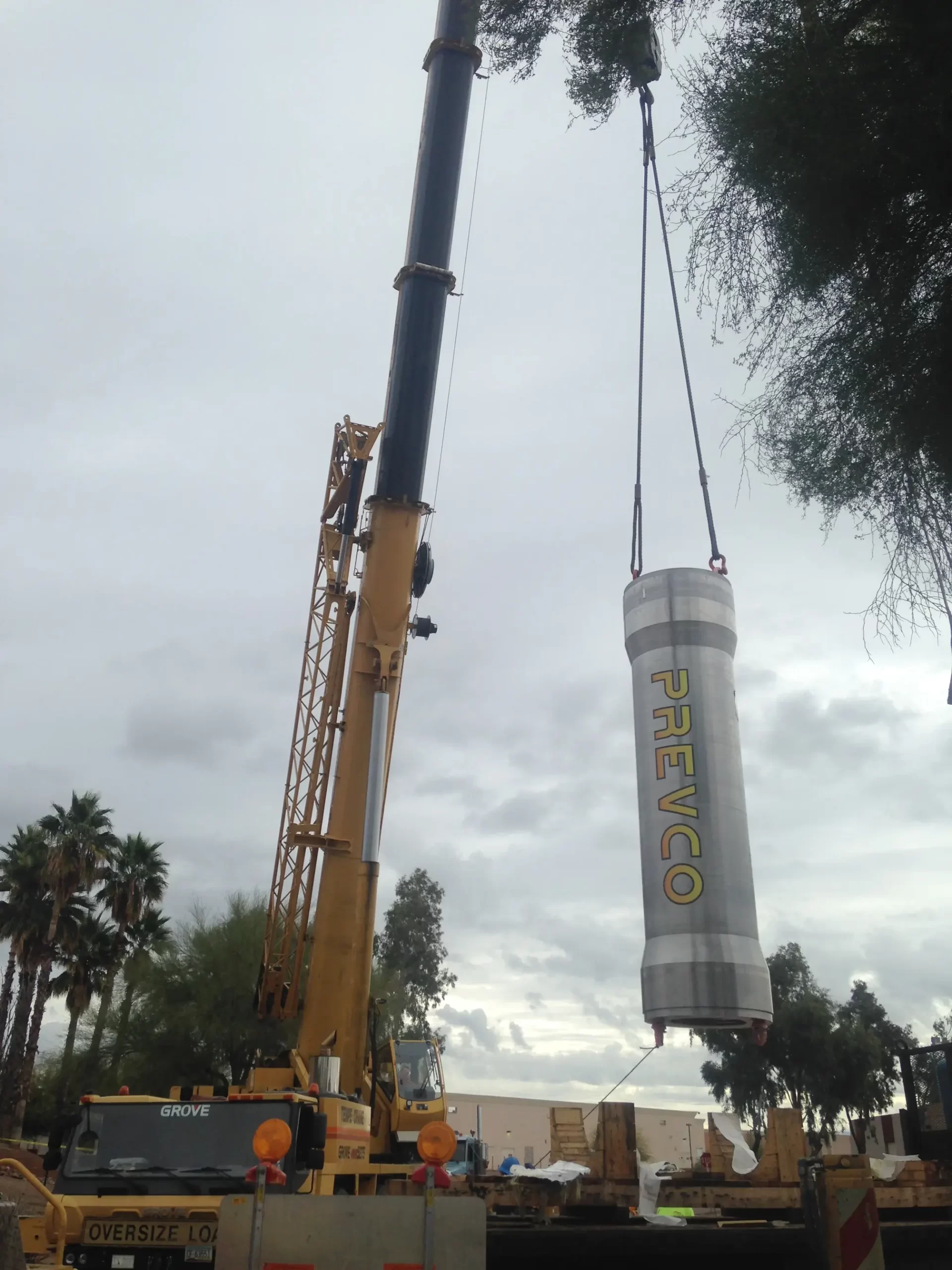Dual cranes collaborate to maneuver a piece of specialized industrial equipment, showcasing operational synergy.