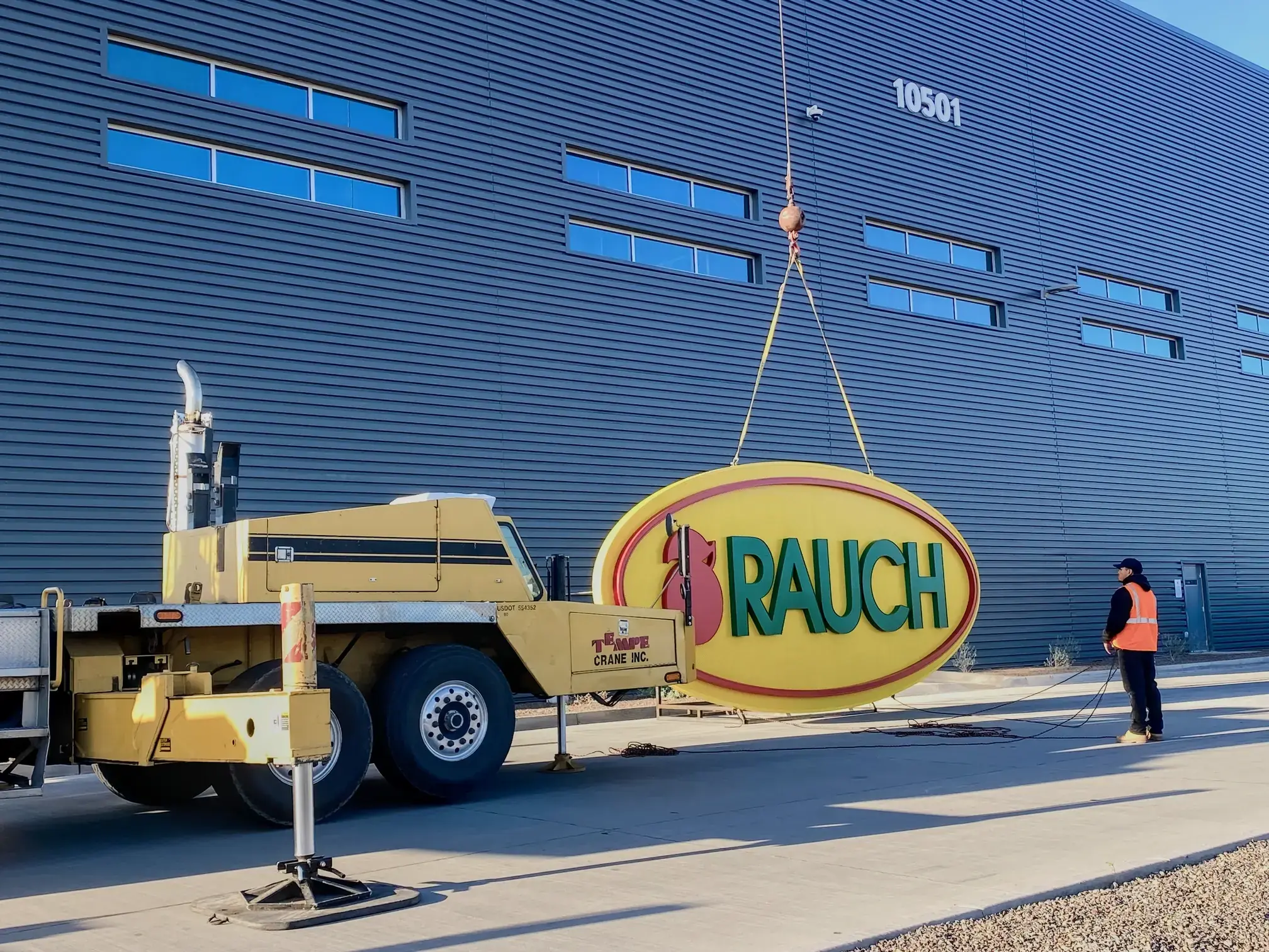 A crane preparing to lift large commercial signage into place, symbolizing the impact of our services on commercial visibility.