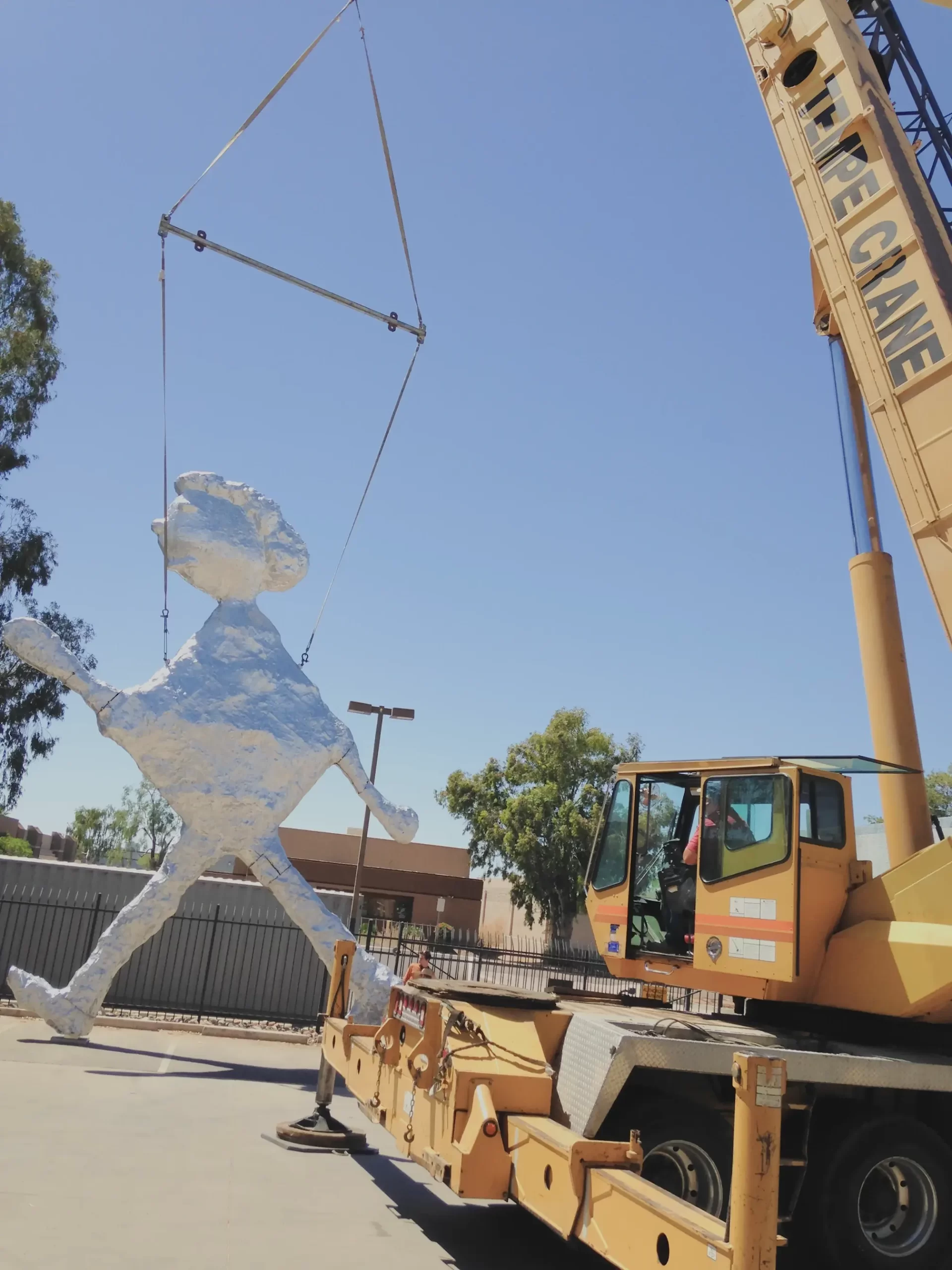A crane carefully positions a large sculpture, highlighting our involvement in cultural projects.
